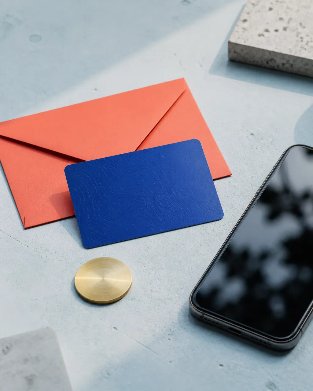 A points card, envelope, token, and smartphone arranged on a pale workbench